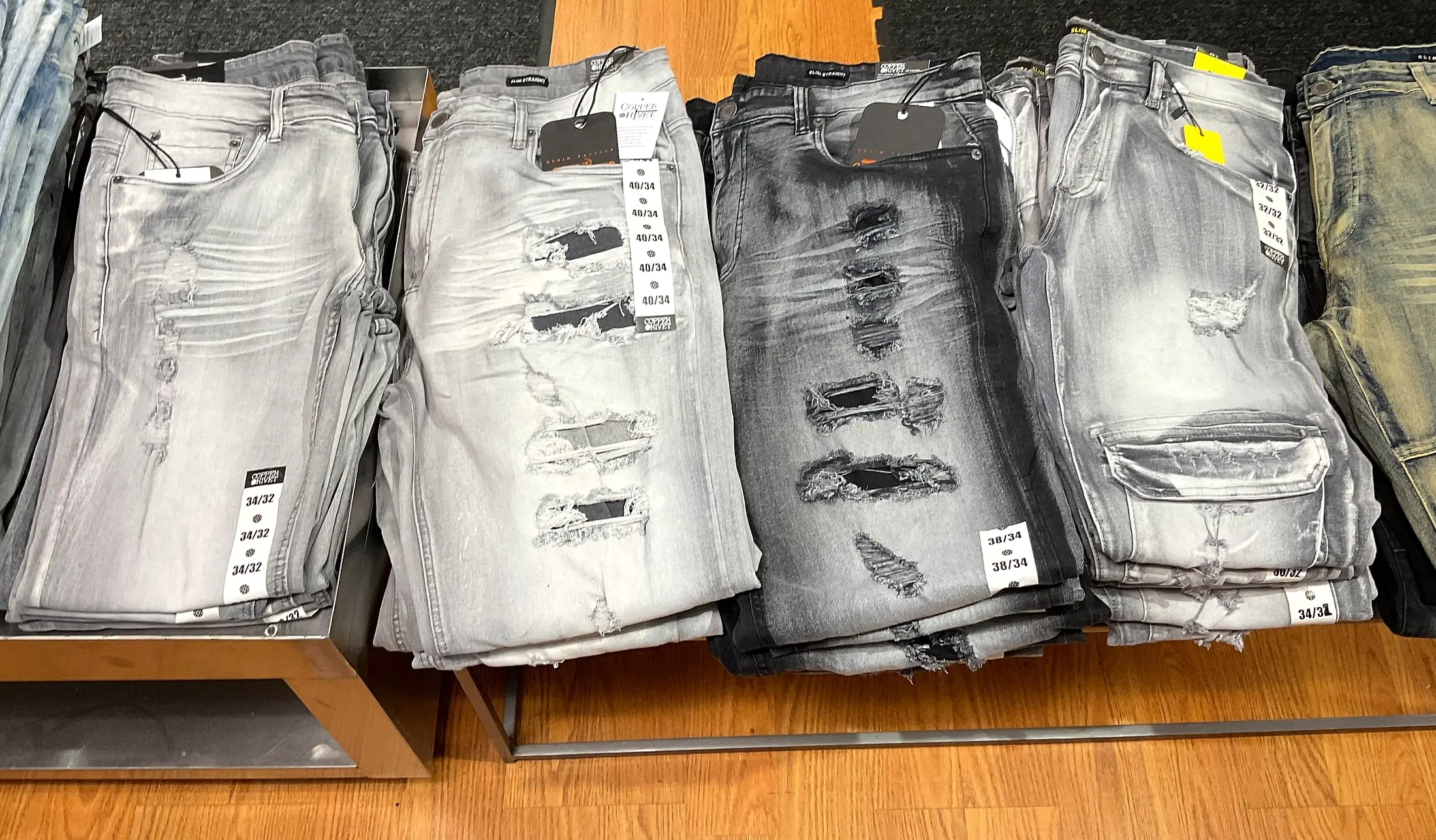Stacks of gray ripped and distressed jeans on a display table