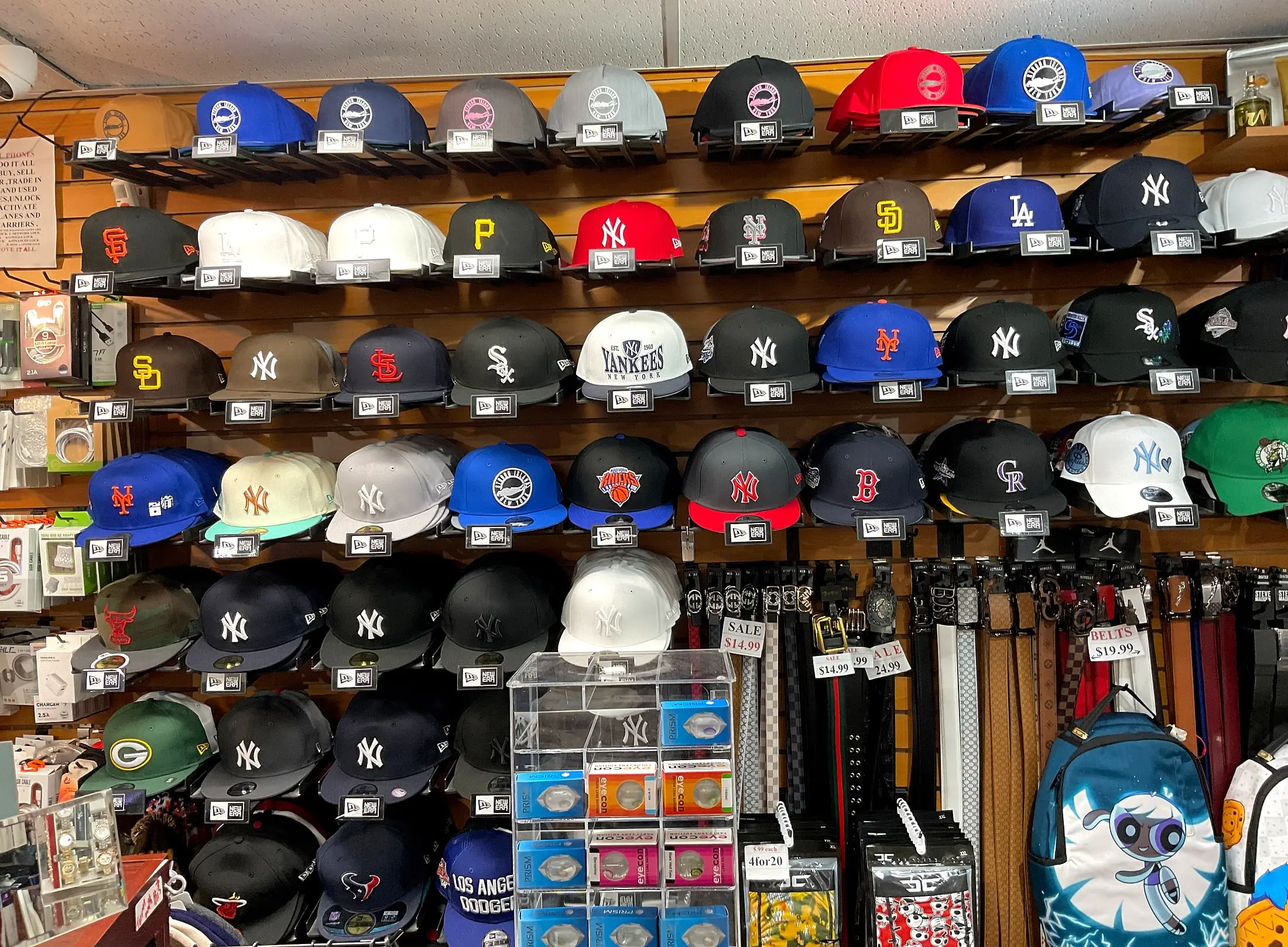 A wall of fitted team caps next to a rack of belts