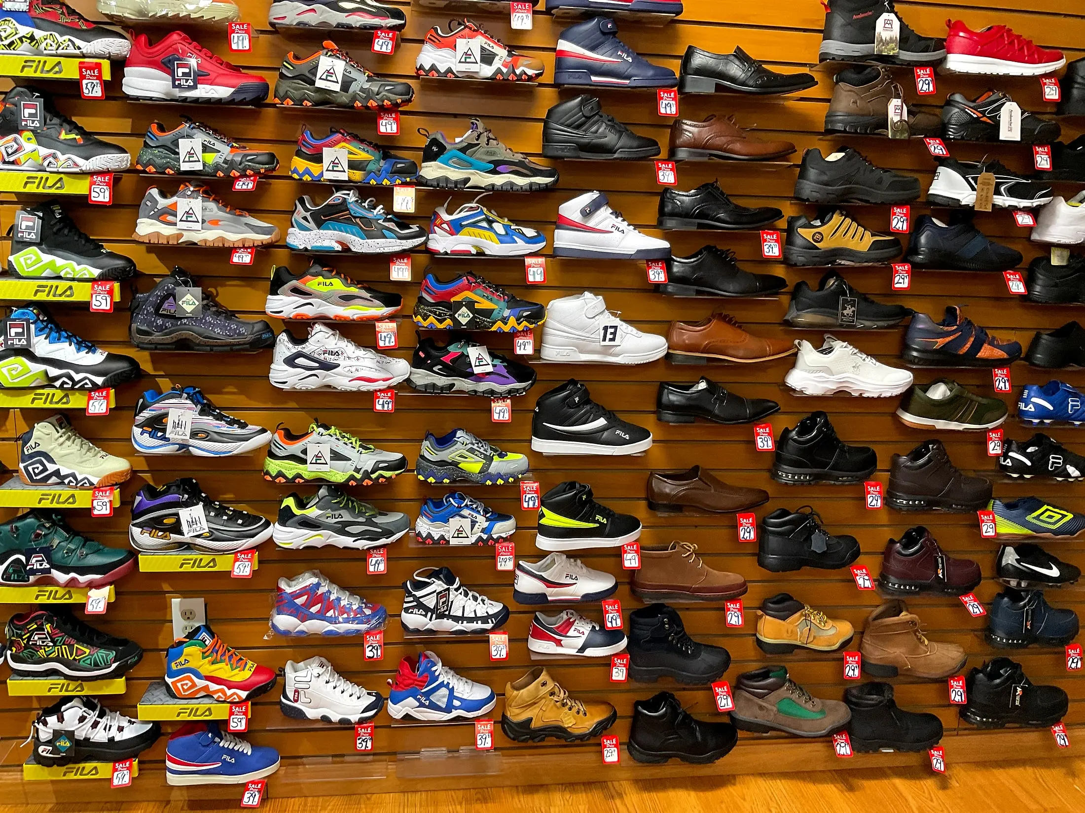 A wall of Fila sneakers, dress shoes, and boots with sale tags