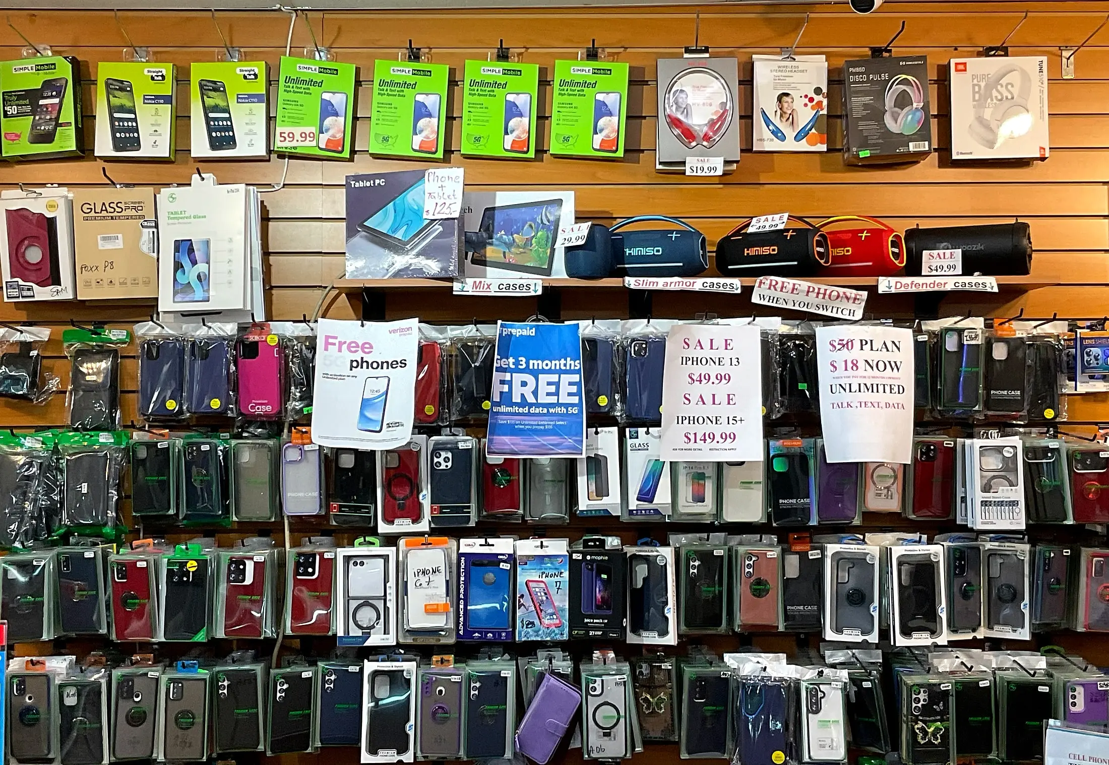 Phone cases, headphones, and speakers on the wall, with signs for phone and plan deals