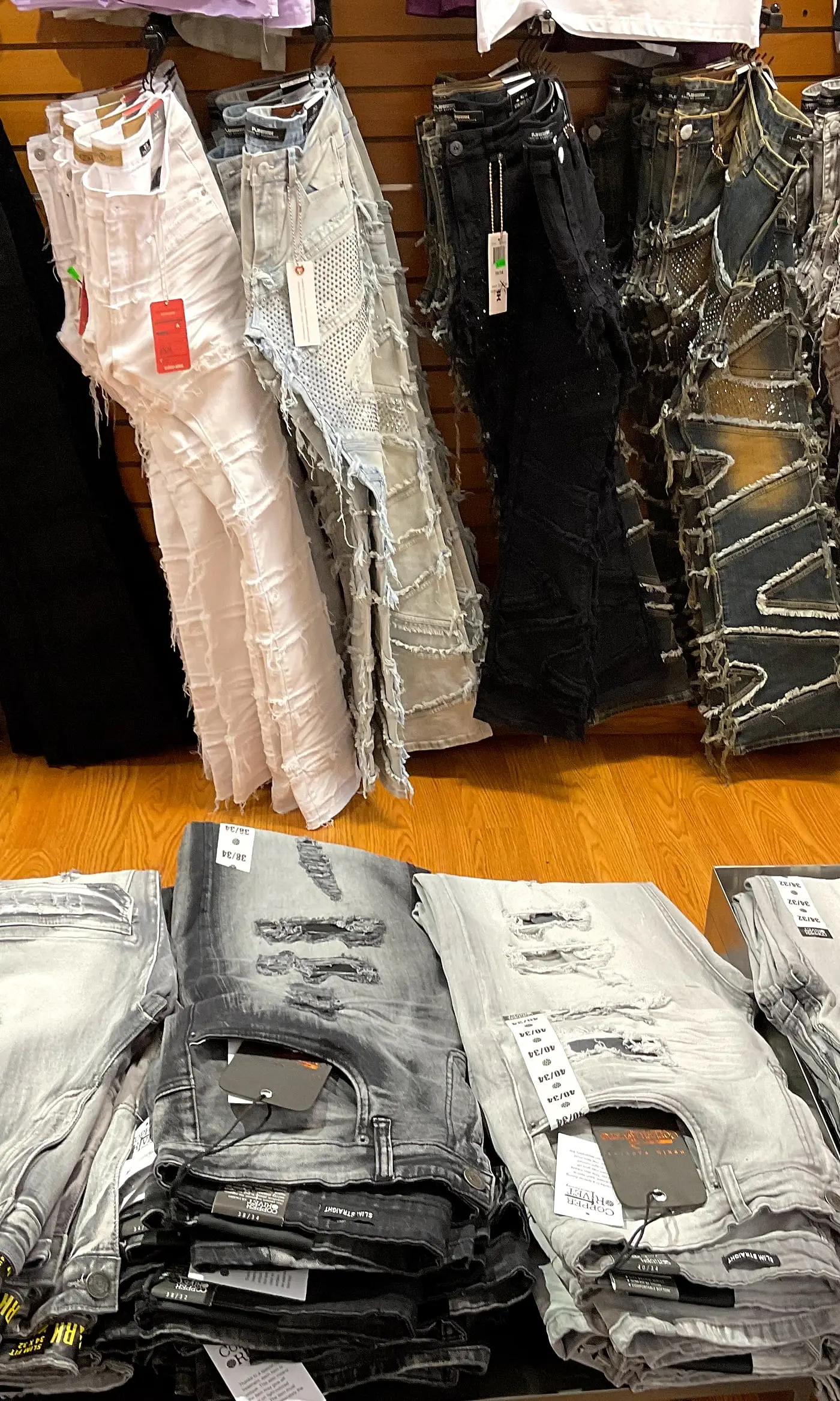 Frayed designer jeans hanging above tables of folded jeans