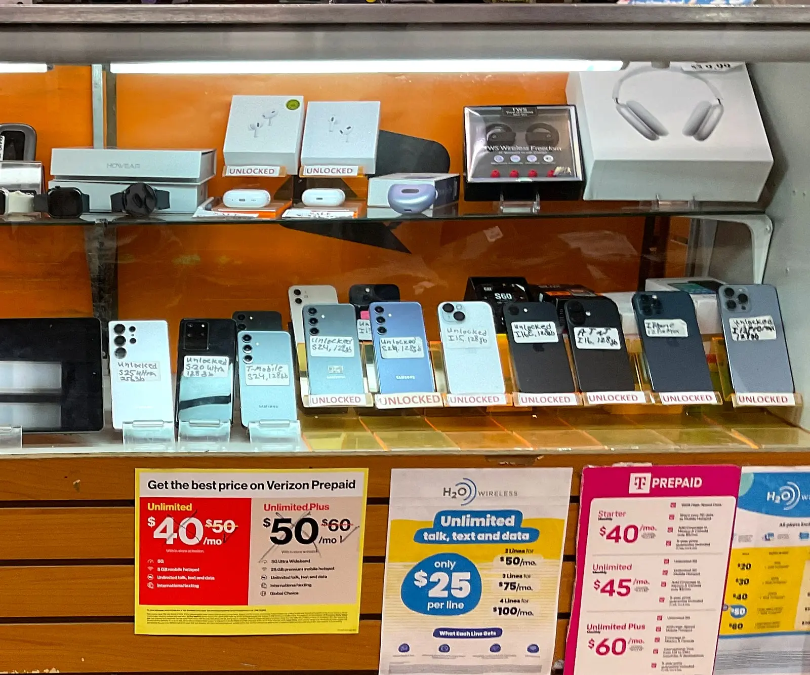 Unlocked smartphones in a glass display case above prepaid plan signs