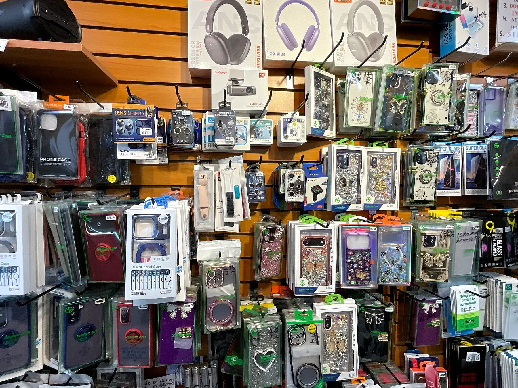 Headphones, camera lens protectors, and decorated phone cases on the accessories wall